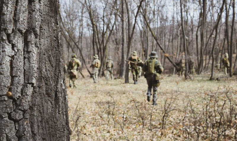 A group of airsoft players running in a wood