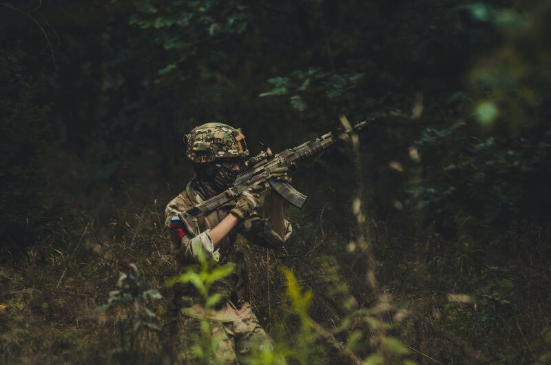 An airsoft player in the woods with a airsoft gun